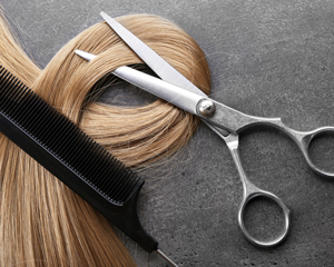 scissors and comb with long hair on a gray surface hair cutting tools for salon use