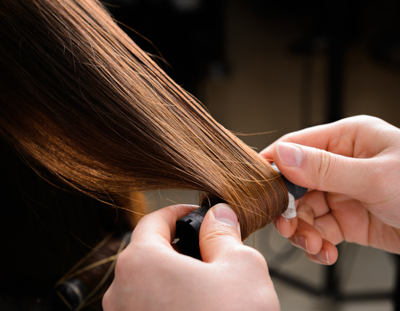 hands styling silky hair with curling tool for smooth finish