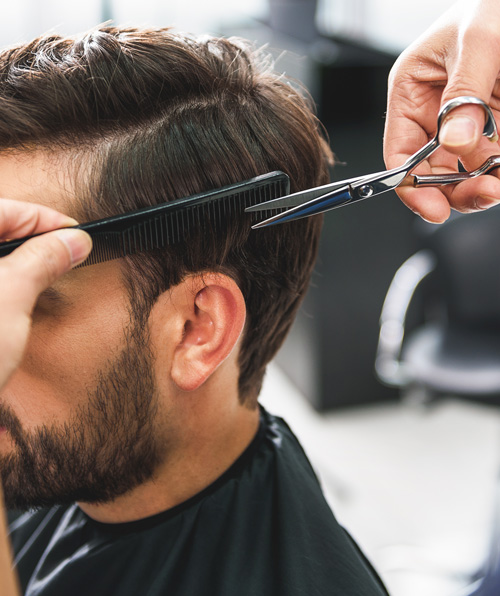 haircut process with man getting trimmed using scissors and comb in barbershop professional grooming services