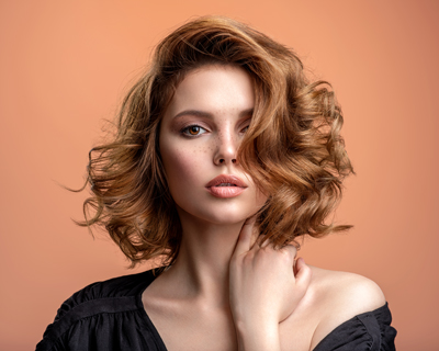 portrait of a woman with stylish curly hair against an orange backdrop showcasing beauty and fashion trends in hairstyle 2 elegance and confidence
