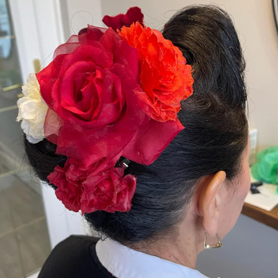 woman with elegant hairdo adorned with vibrant red and orange flowers suitable for cultural celebrations