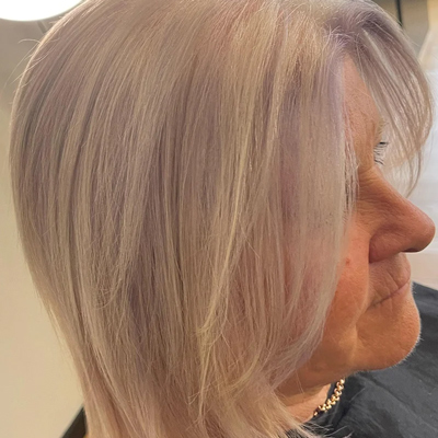woman with shoulder length hair featuring a light lavender tint styled in a smooth lob hairstyle
